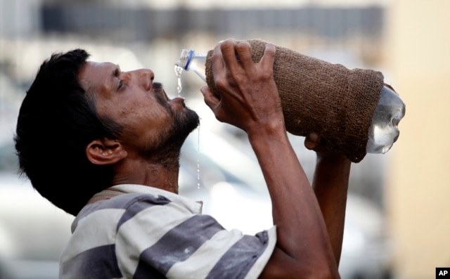 FILE - An Indian drinks water from a bottle on a hot summer day in Allahabad, India.