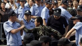 Police officers arrest a protester during a protest against plans to expand a petrochemical plant in Ningbo, Zhejiang province, China, October 27, 2012. 
