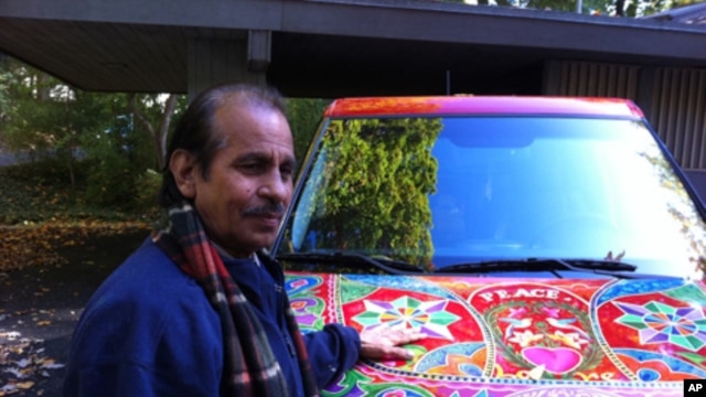 Pakistani truck and bus artist Ghulam Sarwar stands in front of a car he recently painted.