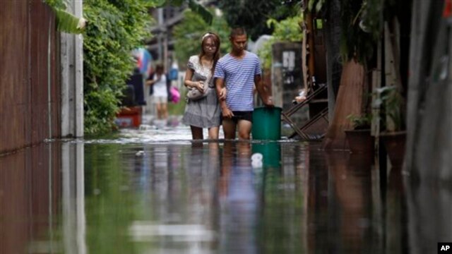 Cư dân lội qua một khu vực ngập lụt ở Bangkok. Các nhà khoa học nói rằng mực nước biển đang tăng lên và thủ đô Thái Lan có thể chìm vĩnh viễn dưới làn nước trong vài thập niên nữa.