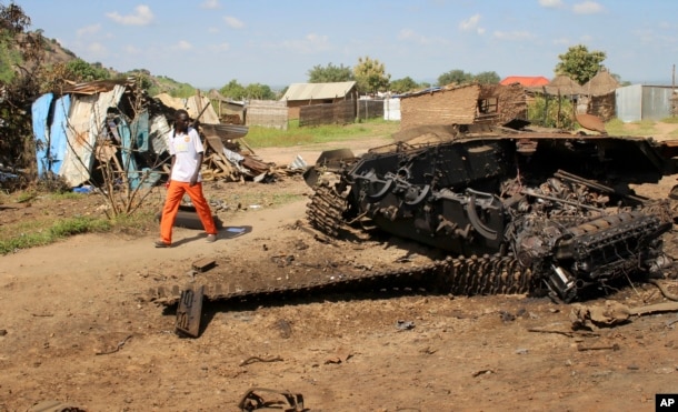 FILE - A man walks past the remains of a tank destroyed during fighting between government and rebel forces in the Jebel area of the capital, Juba, South Sudan, July 16, 2016.