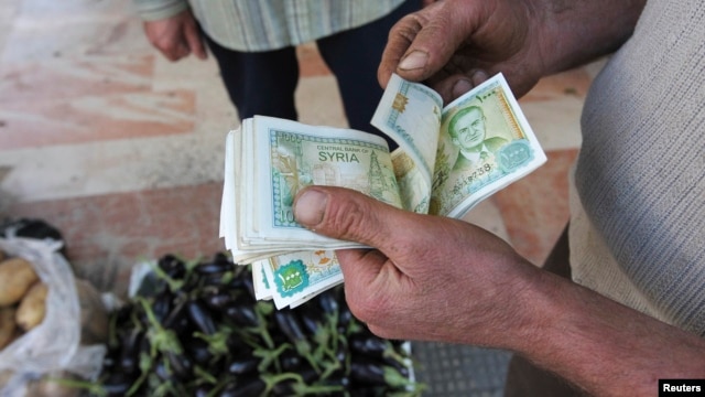 FILE - Um vendedor conta notas da moeda sírias em Damasco, 13 de novembro de 2012.