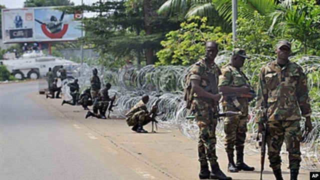 Armed members of the New Forces adopt combat positions near the hotel that houses the rival government declared by Alassane Ouattara in Abidjan, Ivory Coast, 13 Dec 2010