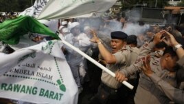 Indonesian police officers react to tear gas fired by their colleagues as they scuffle with Muslim protesters during a demonstration against American-made film 'Innocence of Muslims', September 17, 2012.