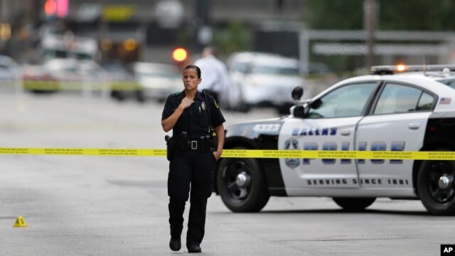 A Dallas police officer guards the scene of last night's shooting as investigators work in downtown Dallas on July 8, 2016. 