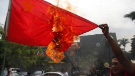 Hành động lấn lướt của Trung Quốc ở biển Đông đã làm bùng ra nhiều cuộc biểu tình bài Bắc Kinh tại các quốc gia cũng có tuyên bố chủ quyền ở biển Đông. Trong ảnh là một người biểu tình Philippines đốt cờ của Trung Quốc.