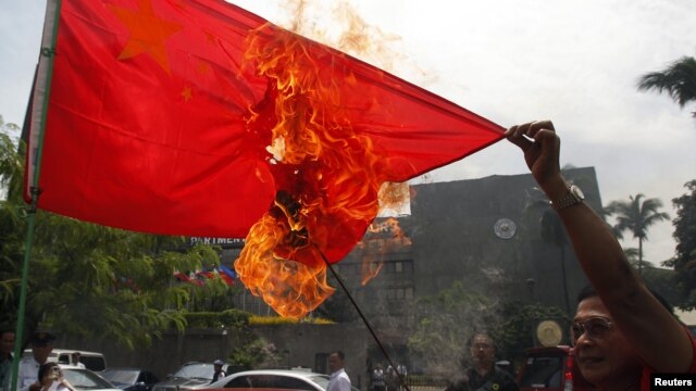 Hành động lấn lướt của Trung Quốc ở biển Đông đã làm bùng ra nhiều cuộc biểu tình bài Bắc Kinh tại các quốc gia cũng có tuyên bố chủ quyền ở biển Đông. Trong ảnh là một người biểu tình Philippines đốt cờ của Trung Quốc.