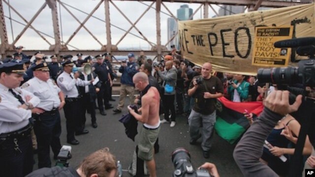 A police officer with a bullhorn addresses a  large group of protesters affiliated with the Occupy Wall Street movement who attempted to cross the Brooklyn Bridge, effectively shutting parts of the roadway down, Saturday, Oct. 1, 2011 in New York.