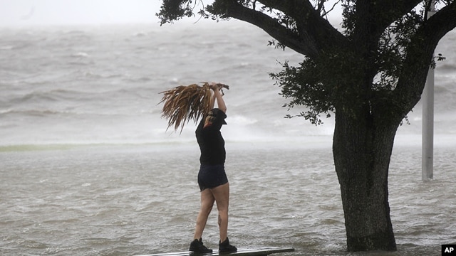 A woman stands on a partially submerged picnic bench in the storm surge from Isaac, on Lakeshore Drive along Lake Pontchartrain, as the storm approaches landfall, in New Orleans, Aug. 28, 2012. 