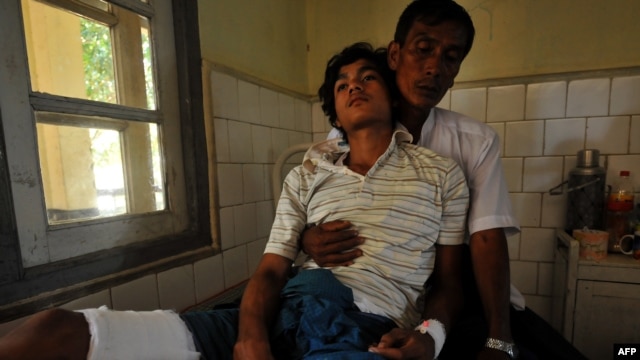 Một người đàn ông Phật giáo bị thương và cha tại một bệnh viện ở Sittwe, thủ phủ của tiểu bang Rakhine.