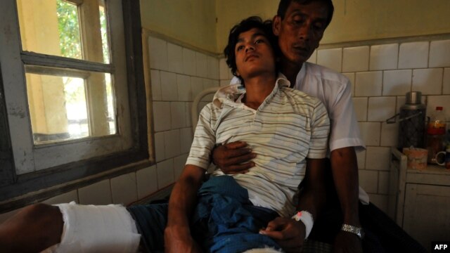 An injured Rakhine Buddhist man leans on his father at a hospital in Sittwe, the capital of Myanmar's western Rakhine state after they were recently injured at the four different districts outside Sittwe, October 26, 2012.
