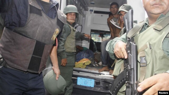 Militares venezolanos evacuan a heridos durante la requisa en el centro penitenciaría de Uribana.