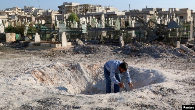 A man inspects a hole in the ground after what activists said was an airstrike by forces loyal to Syria's President Bashar al-Assad in Khan Sheikhoun, northern Idlib province, Dec. 26, 2014. 