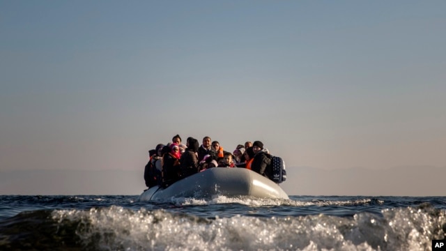 FILE - Refugees and migrants approach the Greek island of Lesbos on a dinghy after crossing the Aegean sea from the Turkish coast, on Monday, Dec. 7, 2015. 