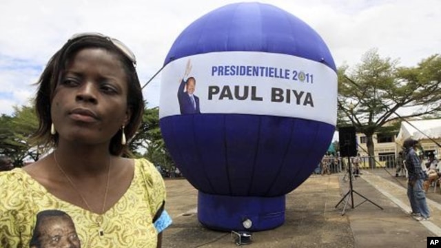 A supporter of Cameroon President Paul Biya stands next to a giant election campaign ball in Yaounde, Cameroon, October 8, 2011.