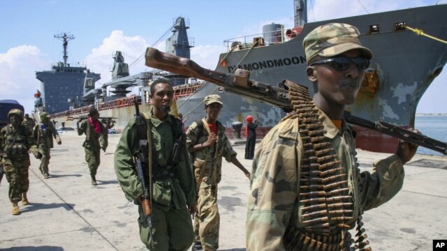Somali National Army soldiers and pro-government Ras Kamboni brigadiers walk along seaport quay, Kismayo, Nov. 2, 2012.