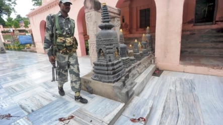 Một nhân viên an ninh Ấn Độ đi bên cạnh các vết chân đẫm máu bên trong ngôi đền Mahabodhi, sau một loạt các vụ nổ tại chùa Bodh Gaya (Bồ Đề Đạo Tràng), ngày 7/7/2013.