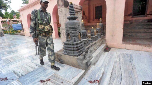 Một nhân viên an ninh Ấn Độ đi bên cạnh các vết chân đẫm máu bên trong ngôi đền Mahabodhi, sau một loạt các vụ nổ tại chùa Bodh Gaya (Bồ Đề Đạo Tràng), ngày 7/7/2013.