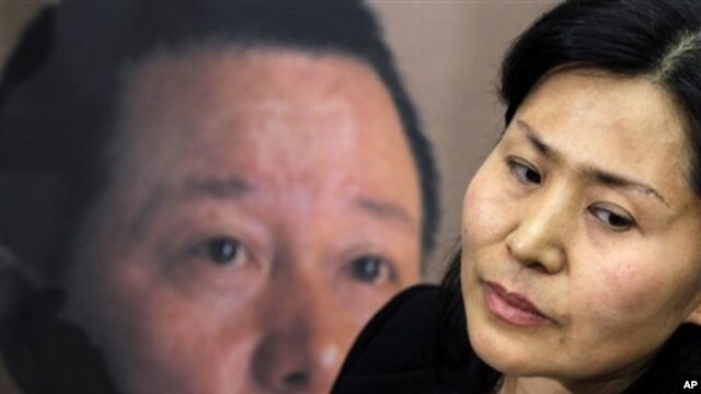 Geng He, wife of disappeared Chinese human rights lawyer Gao Zhisheng, seen on poster at rear, is interviewed before a news conference with Rep. Chris Smith, R-N.J., on Capitol Hill in Washington,  Jan. 18, 2011, where he called attention to human rights 