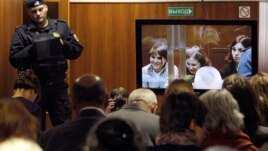 A bailiff stands in a room as people watch a live broadcast of a court hearing on members of the female punk band 'Pussy Riot' in Moscow October 10, 2012.