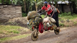People ride with their belongings on a wooden bicycle as they flee from renewed fighting between Congolese army and M23 rebels near the eastern Congolese city of Goma, July 24, 2012.
