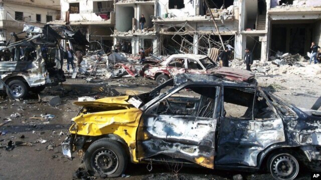 Ciudadanos sirios observan el lugar donde dos bombas explotaron en el barrio progubernamental de Zahraa, en Homs, Siria, el domingo, 21 de febrero de 2016.