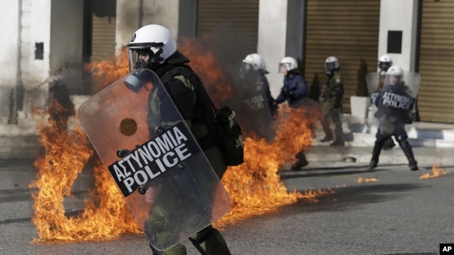 Riot policemen dodge petrol bombs thrown by protesters during a rally in Athens, Nov. 12, 2015. Clashes have broken out as the country faces its first general strike since the Greece's left-led government came to power in January.