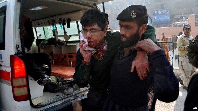 Un guardia de seguridad ayuda a un estudiante herido luego del ataque a la escuela militar en Peshawar, Pakistán.
