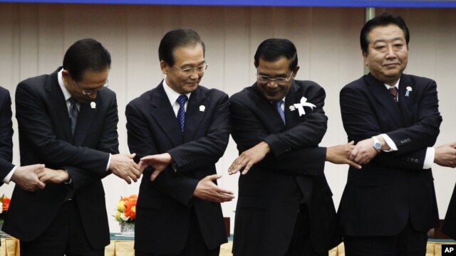From left: South Korea's President Lee Myung-bak, China's Premier Wen Jiabao, Cambodia's Prime Minister Hun Sen and Japan's Prime Minister Yoshihiko Noda prepare to join hands together for a group photo during the ASEAN Plus Three (APT) Commemorative Summit in Phnom Penh, Cambodia, Monday, Nov. 19, 2012. (AP Photo/Vincent Thian)