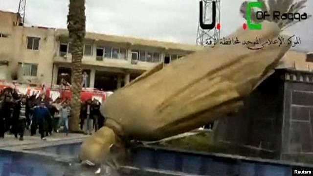 A statue of President Bashar Al-Assad's father, Hafez Al-Assad, is pulled down as people celebrate in Raqqa Mar. 4, 2013.