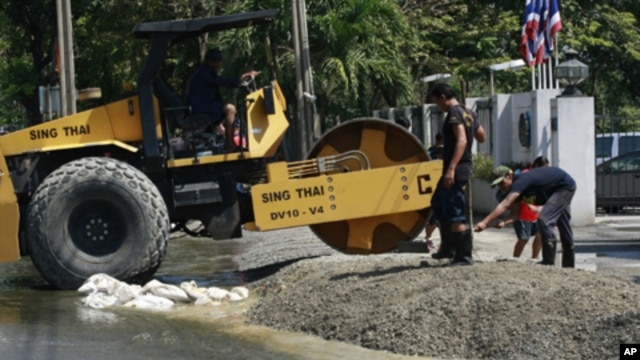 Workers fix the entrance to an air force cadet school near Don Muang airport as flood waters approach Tuesday, Oct. 25, 2011 in Bangkok, Thailand.
