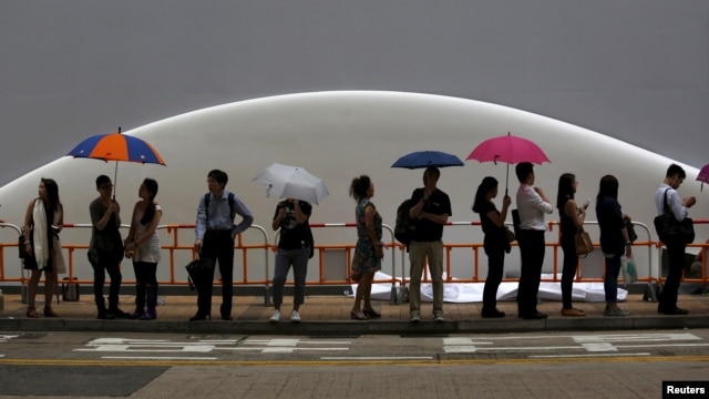 People wait for a bus leaving a shopping district in Hong Kong as Typhoon Linfa approaches, July 9, 2015.