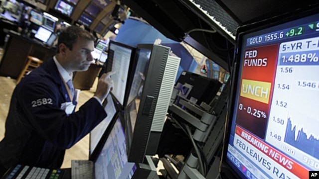 A television monitor shows the interest rate decision of the Federal Reserve as specialist Philip Finale works on the floor of the New York Stock Exchange, June 22, 2011.