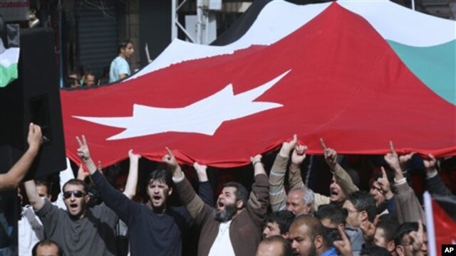 Jordanian supporters of the Islamic Action Front carry a national flag as they shout slogans during a protest in Amman, Jordan, February 25, 2011