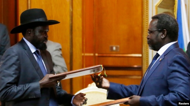 FILE - South Sudan's President Salva Kiir (L) and the country's rebel leader, Riek Machar, exchange signed peace agreement documents in Addis Ababa May 9, 2014.