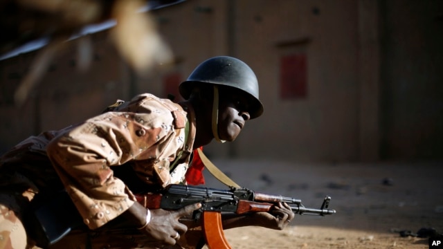 Un soldat malien s'abrite derrière un véhicule à Gao lors d'échanges de tirs avec des djihadistes (10 fév. 2013)