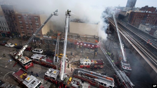 Bomberos combaten las llamas de un incendio desatado al colapsar un edificio en East Harlem, Nueva York.