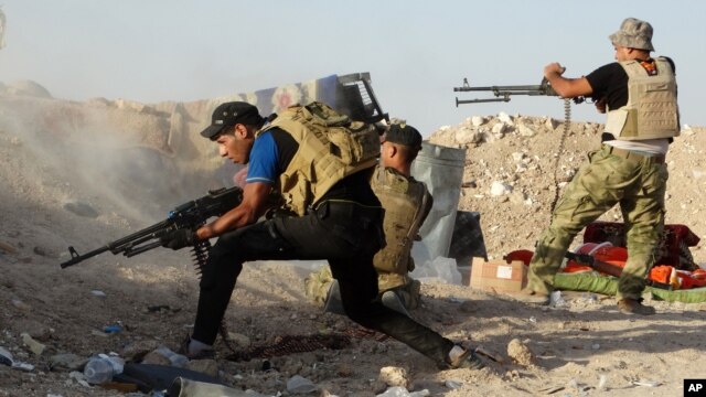 Iraqi security forces defend their positions against an Islamic State group attack in Husaybah, Iraq, June 15, 2015. 
