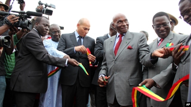Senegalese President Abdoulaye Wade cuts the ribbon at the ceremony next to his son, State Minister for Air Transport Karim Wade
