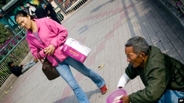 一名妇女走过广州街头一名乞讨的乞丐 （资料照片）
