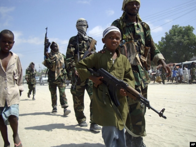 FILE - A young boy leads hard-line Islamist al-Shabab fighters as they conduct military exercises in northern Mogadishu's Suqaholaha neighborhood, Somalia.