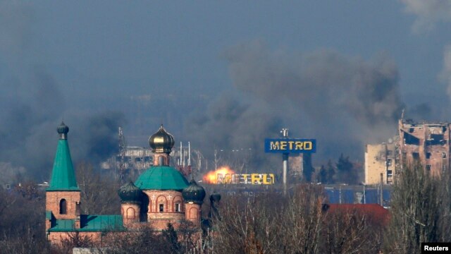 Smoke rises above an old terminal, left, and an administrative building of the airport after the recent shelling during fighting between pro-Russian separatists and Ukrainian government forces in Donetsk, eastern Ukraine, Nov. 9, 2014.