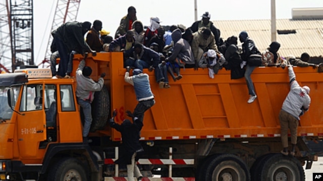 Migrant workers from Africa jump off a truck after arriving in Misrata port during an evacuation operation organized by IOM (International Organization for Migration), April 23, 2011
