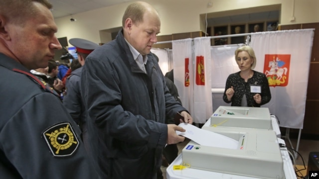 A man casts his ballot paper at a polling station in the town of Khimki outside Moscow, Russia, October 14, 2012. 