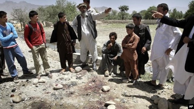 Afghans stand around the bloodstains at the scene of a suicide attack in Kapisa, northeast of Kabul, Afghanistan, June 15, 2011