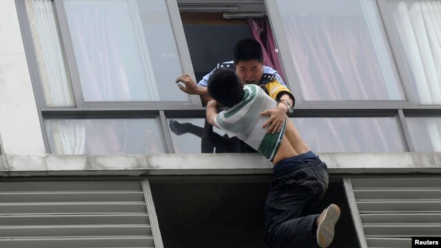 A police officer grabs a man who tries to jump off the 7th floor of a hotel in Chengdu, China. (May 2014)