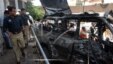 Pakistani police officers visit the site of an explosion in Peshawar, Pakistan on Friday, May 24, 2013. Police say a suicide bomber walked up to a vehicle owned by an Afghan religious leader in northwestern Pakistan and set off his explosives, killing sev
