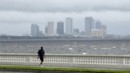 A resident walks along Bayshore Boulevard in between squalls blowing across the bay in Tampa, Florida, Monday, Aug. 27, 2012.