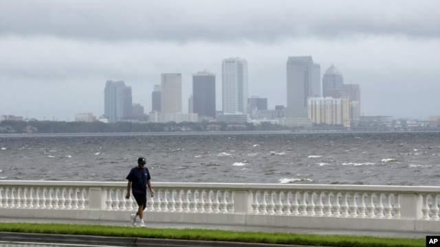 A resident walks along Bayshore Boulevard in between squalls blowing across the bay in Tampa, Florida, Monday, Aug. 27, 2012.