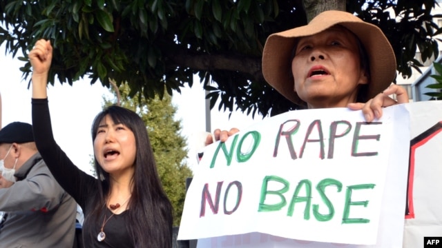 Civic group members shout slogans and hold placards as they attend a protest over the alleged rape of a local woman by two US servicemen in Okinawa, in front of the prime minister's official residence in Tokyo, Oct. 20, 2012.